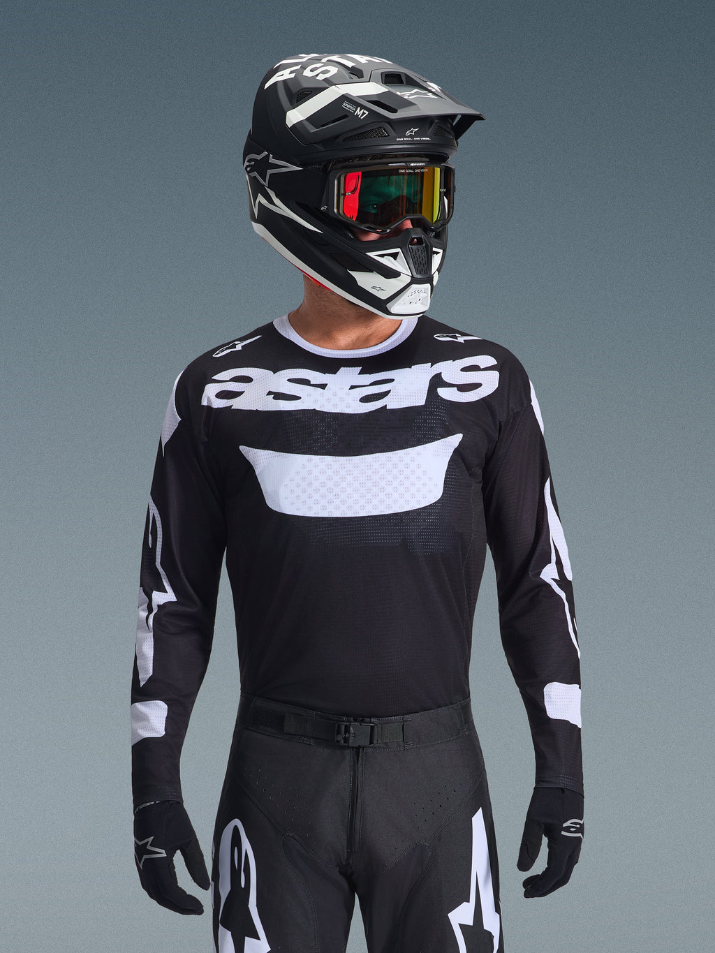 Alpinestars 2026 Racer Air Riway Jersey, jersey de motocross en blanco y negro con marca 'astars', usado por un piloto con casco, gafas y pantalones negros a juego, con paneles de malla transpirable para carreras todoterreno