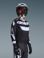 Piloto de motocross con el Jersey Racer Air Riway 2026, jersey negro y blanco con el logo 'astars', casco negro y blanco a juego con gafas de espejo naranjas, pantalones y guantes de motocross negros, equipamiento coordinado para carreras off-road