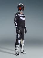 Alpinestars 2026 Racer Air Riway Gear Set, piloto de motocross con equipación completa de competición, jersey negro con marca 'Astars' en blanco y paneles de malla, pantalones negros con logotipos blancos grandes y paneles en las rodillas, casco negro con gafas rojas, botas blancas y negras, conjunto profesional de carreras todoterreno