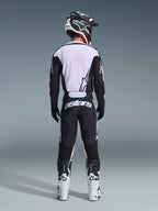 Alpinestars 2026 Racer Air Riway Gear Set, conjunto de equipamiento de motocross, negro y blanco, vista trasera del piloto con jersey ventilado con paneles de malla blanca, pantalones a juego con marca astars llamativa en el asiento, coordinado con botas y casco de motocross en blanco y negro