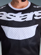 Alpinestars 2026 Racer Air Riway Jersey, jersey de motocross, negro y blanco, primer plano del pecho con logotipo blanco grande, textura detallada de tejido de malla transpirable, equipamiento técnico para conducción off-road
