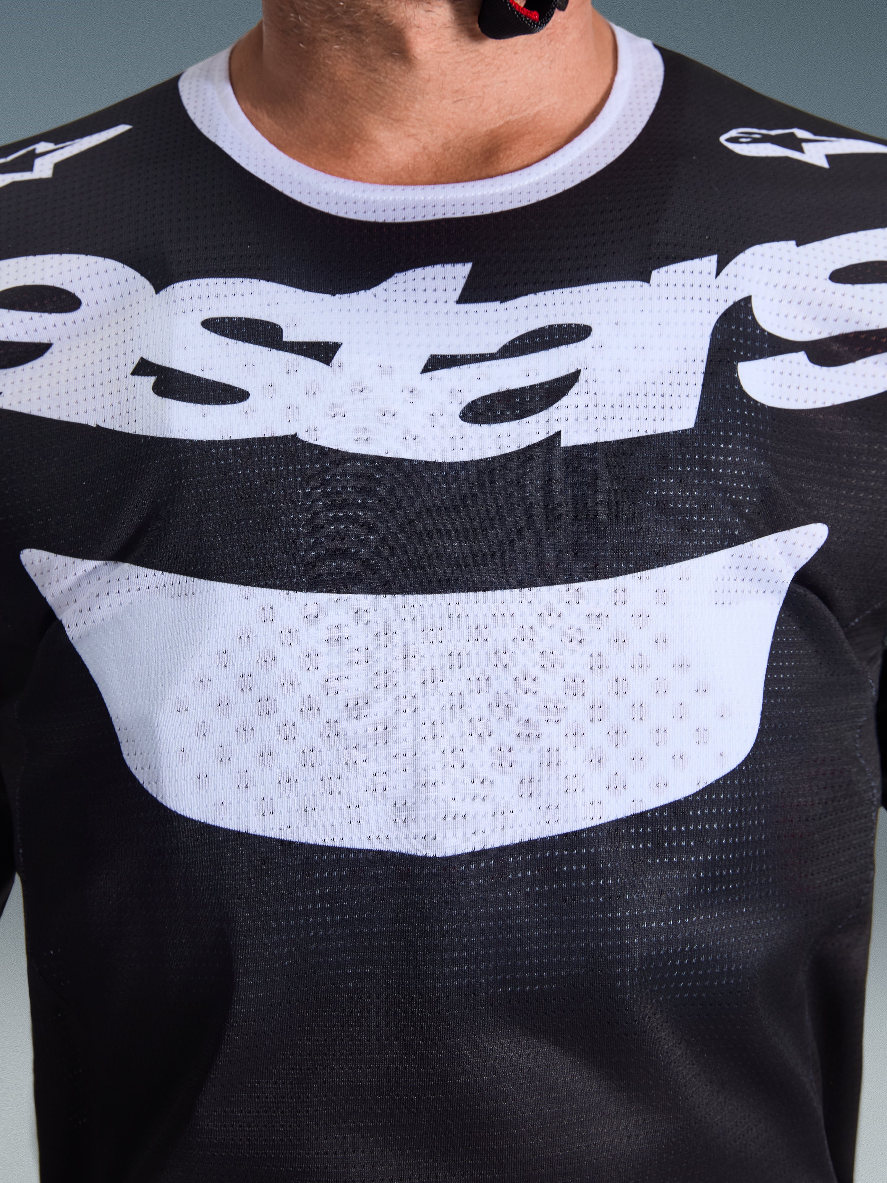 Alpinestars 2026 Racer Air Riway Jersey, jersey de motocross, negro y blanco, primer plano del pecho con logotipo blanco grande, textura detallada de tejido de malla transpirable, equipamiento técnico para conducción off-road