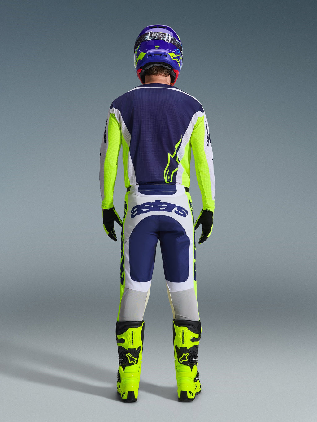 Back view of a motocross rider wearing the Alpinestars 2026 Racer Air Riway Jersey and matching pants in Light Gray Yellow Fluo Blue, paired with bright yellow fluo boots and a coordinated helmet, showing a complete off-road racing gear set.