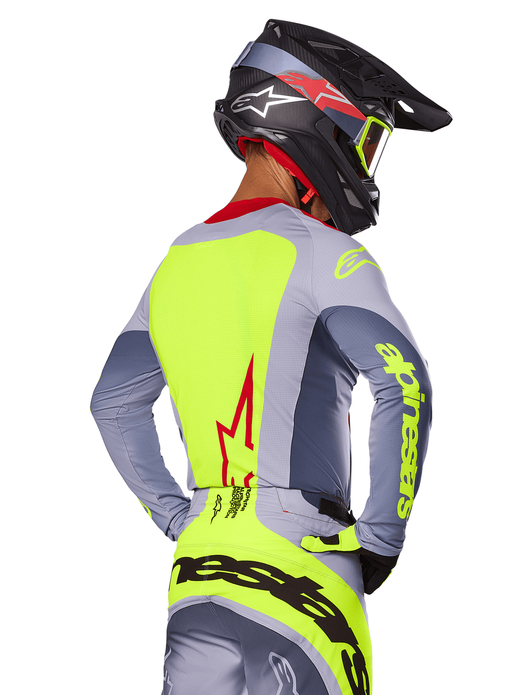 Jersey Alpinestars Techstar Melt 2025, Rojo Brillante Gris, vista trasera de un piloto de motocross con equipamiento de carreras gris y amarillo neón, logotipo de estrella roja en la espalda, casco negro y rojo a juego, indumentaria técnica para off-road