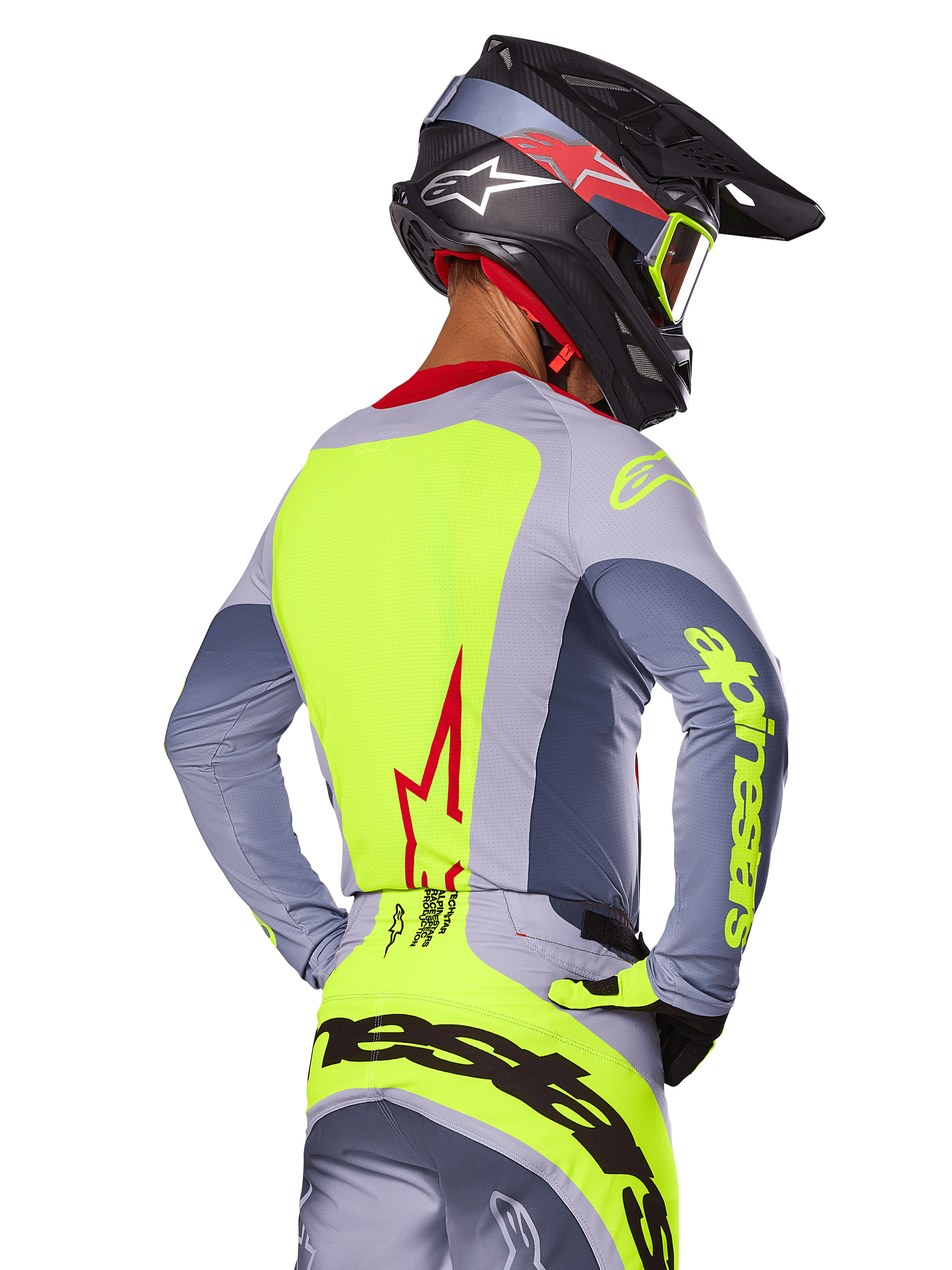 Jersey Alpinestars Techstar Melt 2025, Rojo Brillante Gris, vista trasera de un piloto de motocross con equipamiento de carreras gris y amarillo neón, logotipo de estrella roja en la espalda, casco negro y rojo a juego, indumentaria técnica para off-road