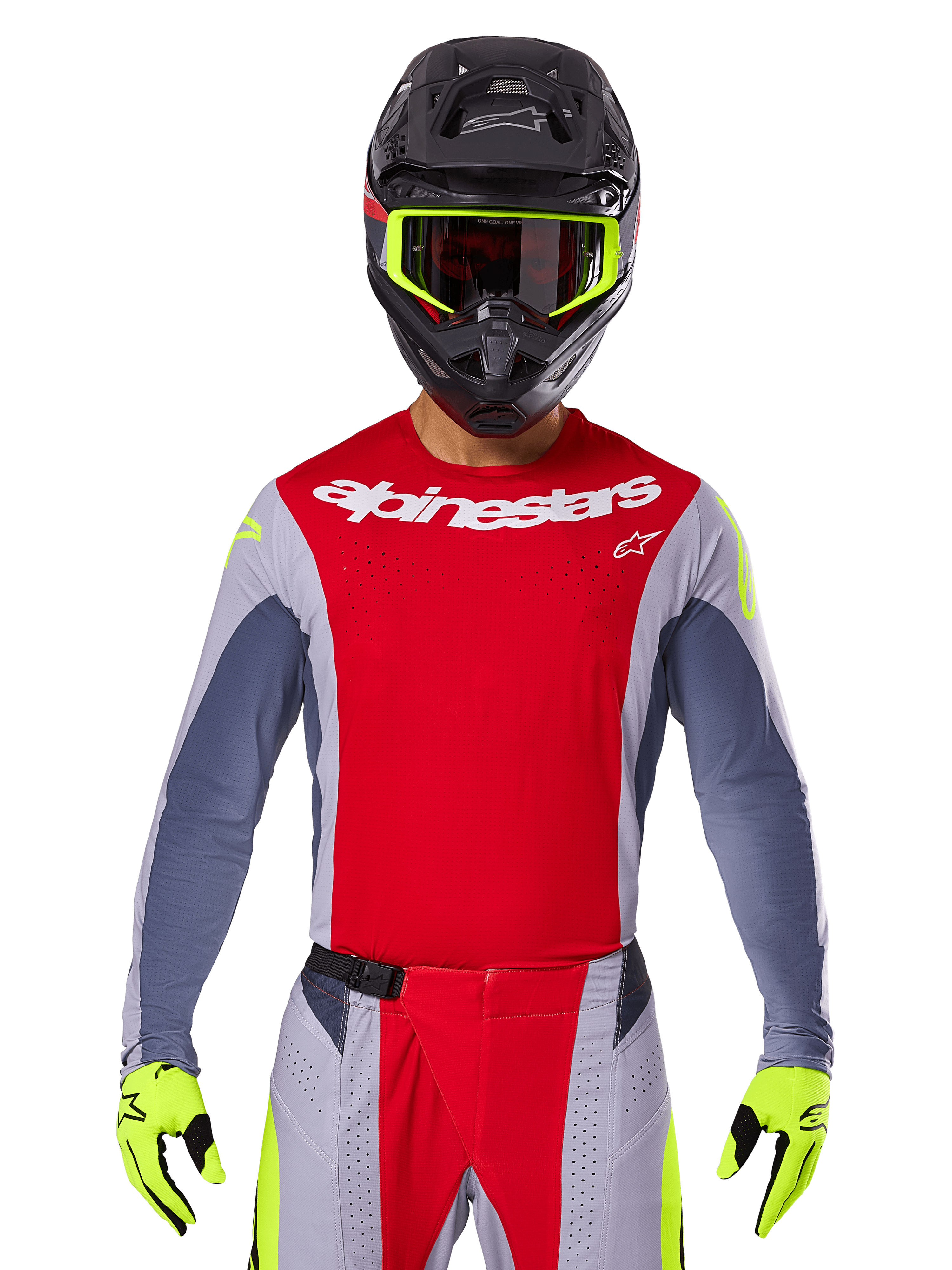Piloto de motocross con Jersey Techstar Melt 2025 y pantalones a juego, rojo brillante y gris con logotipos de Alpinestars en blanco, casco negro con gafas amarillo neón, guantes amarillo neón a juego, equipamiento de alto rendimiento ventilado para carreras off-road