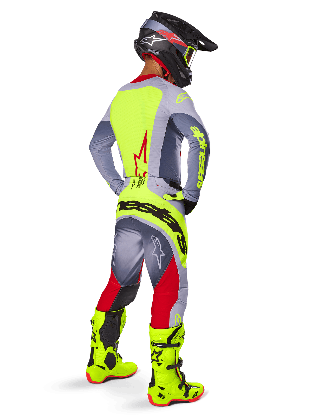 Piloto de motocross visto desde atrás con el jersey Alpinestars Techstar Melt 2025 en Rojo Gris Brillante, con panel trasero amarillo brillante y mangas grises, pantalones grises y rojos a juego con logotipos amarillos, botas de motocross amarillo brillante y casco negro con gafas amarillas, conjunto de competición off-road coordinado