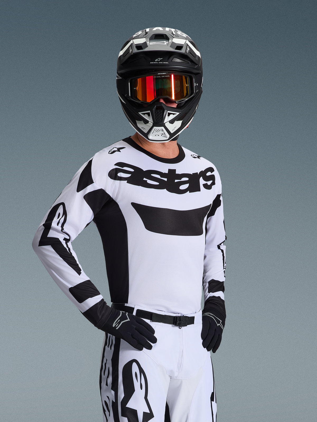 Jersey Alpinestars Racer Riway 2026, jersey de motocross, blanco y negro, con el llamativo logotipo 'astars' en el pecho, usado con pantalones blancos a juego y guantes negros, casco blanco y negro con gafas rojas reflectantes, equipo profesional de carreras off-road