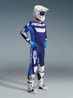 Alpinestars 2026 Racer Riway Jersey en Azul UCLA y Blanco, usado por un piloto de motocross con pantalones a juego, casco blanco, guantes azules y botas blancas, con la llamativa marca 'astars' en el pecho, equipamiento completo de carreras off-road