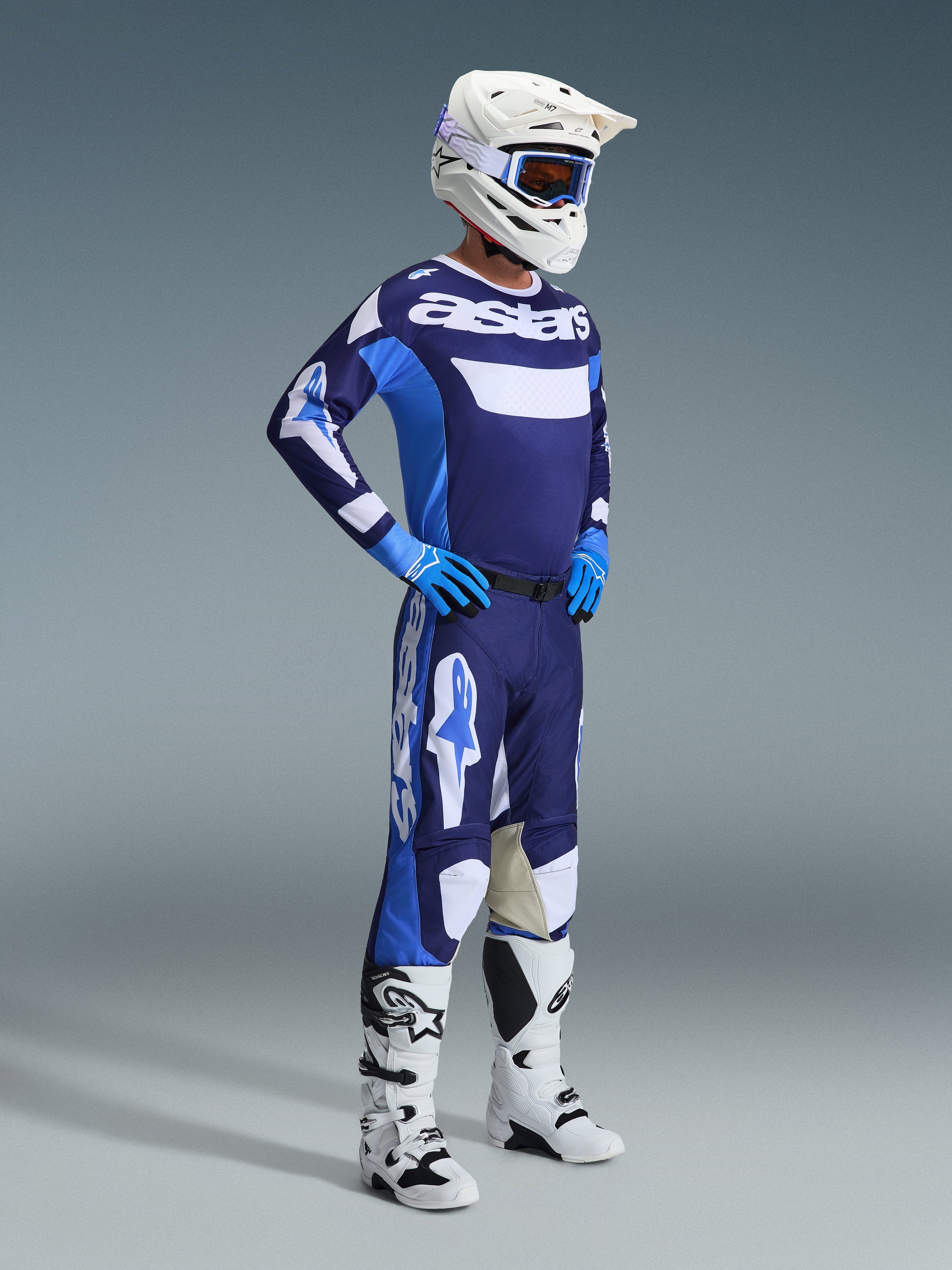 Alpinestars 2026 Racer Riway Jersey en Azul UCLA y Blanco, usado por un piloto de motocross con pantalones a juego, casco blanco, guantes azules y botas blancas, con la llamativa marca 'astars' en el pecho, equipamiento completo de carreras off-road