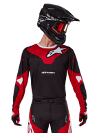 Alpinestars 2025 Racer Veil Jersey, camiseta de motocross, negro y rojo brillante, combinada con pantalones a juego, casco negro y gafas rojas, con logotipos blancos llamativos y un diseño de competición estilizado, equipación de alto rendimiento para motocross