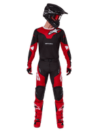 Piloto de motocross con el conjunto Alpinestars 2025 Racer Veil, jersey negro y rojo brillante con logo de Alpinestars en blanco, pantalones de motocross a juego, casco negro con gafas rojas y botas rojas; equipamiento completo de alto rendimiento para conducción off-road