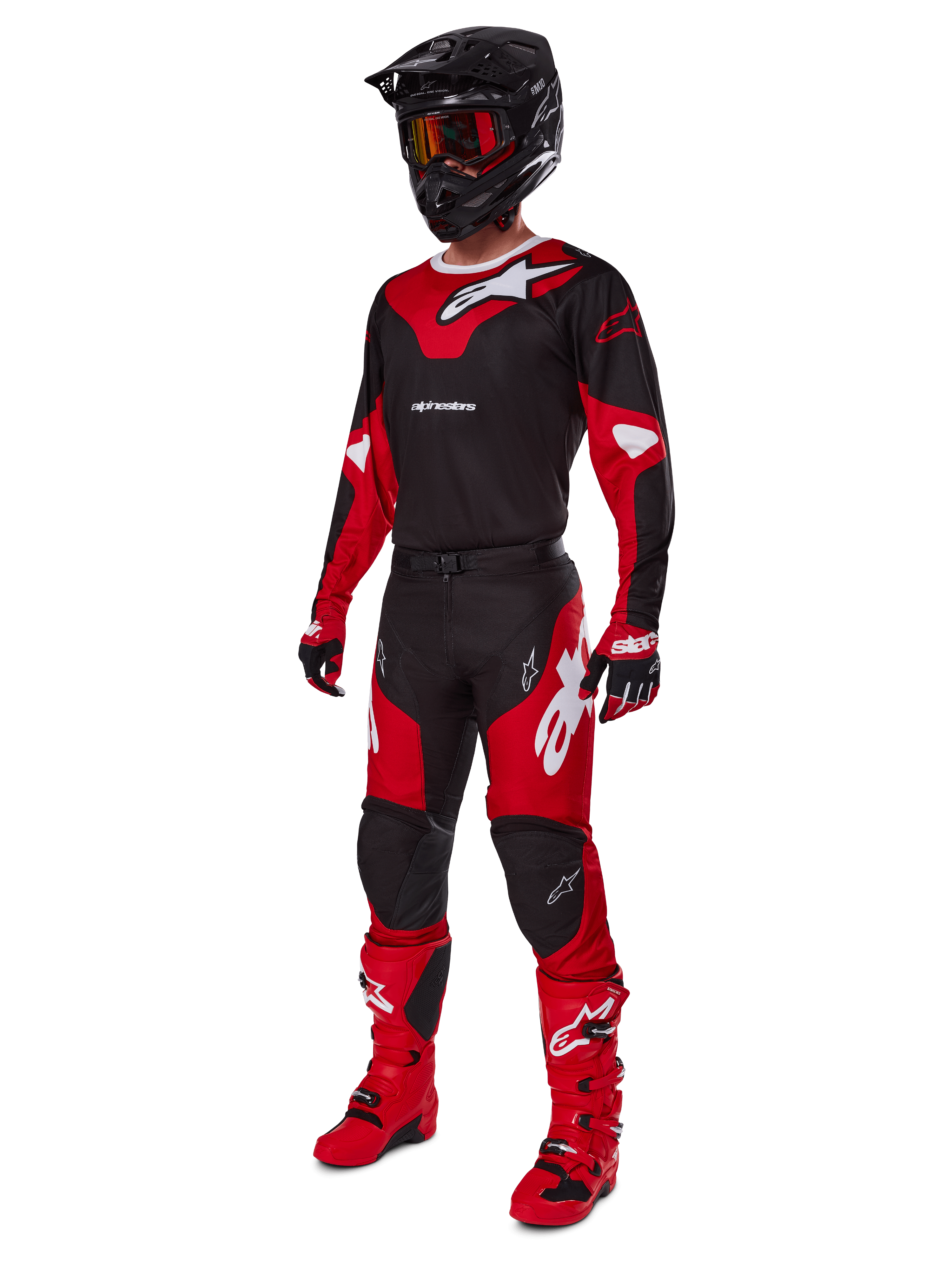 Piloto de motocross con equipamiento completo de competición que incluye el jersey Alpinestars 2025 Racer Veil en negro y rojo brillante, pantalones a juego, botas rojas, casco negro con gafas rojas y guantes rojos y negros, look coordinado de alto rendimiento para carreras off-road