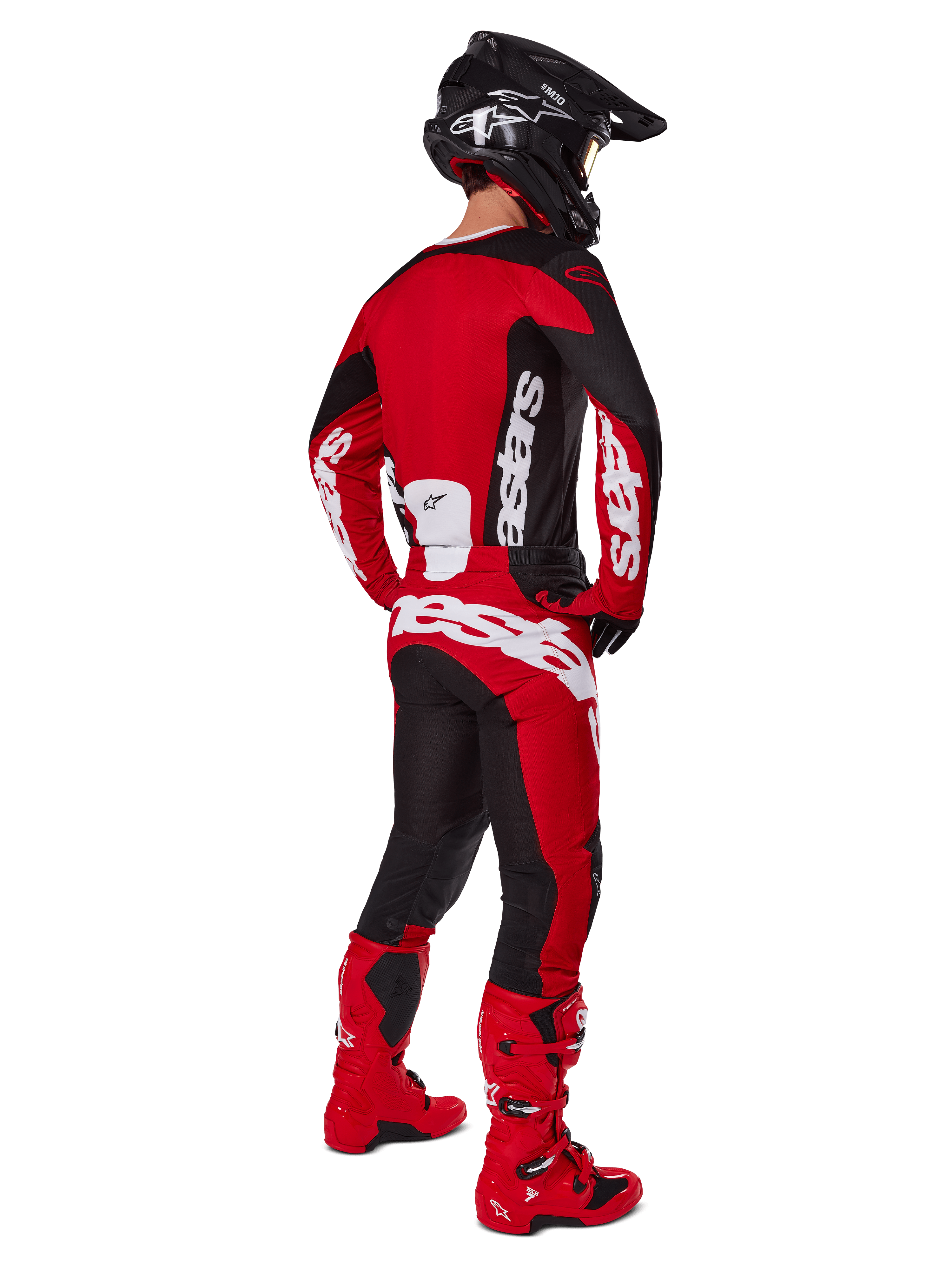 Piloto de motocross visto desde atrás vistiendo el jersey Alpinestars 2025 Racer Veil en negro y rojo brillante, combinado con pantalones rojos y negros a juego y botas de motocross rojas, con grandes logotipos en blanco, ideal para el rendimiento off-road
