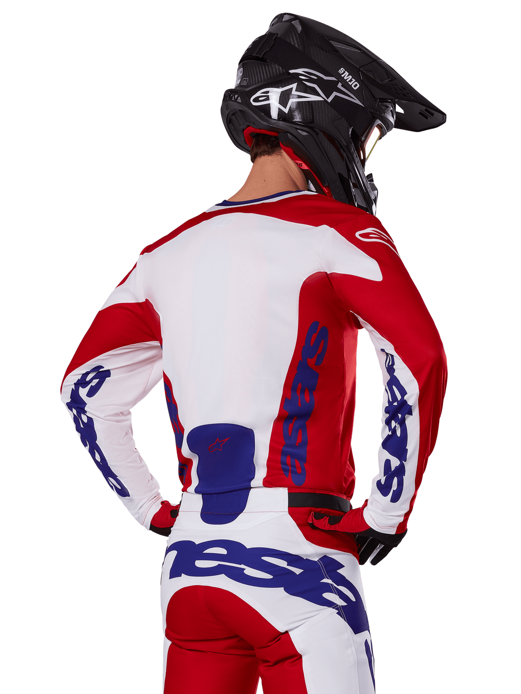 Alpinestars 2025 Racer Veil Jersey y pantalones, conjunto de equipamiento de motocross, rojo brillante, blanco y azul, vista trasera de un piloto con el equipo a juego y casco de motocross negro, con logotipos llamativos de Alpinestars en azul, ropa técnica para carreras off-road