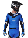 Alpinestars 2025 Racer Veil Jersey, jersey de motocross azul y negro, usado con equipación de motocross a juego que incluye casco y guantes, diseño deportivo con la marca Alpinestars en blanco