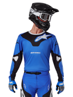 Alpinestars 2025 Racer Veil Jersey, jersey de motocross azul y negro, usado con equipación de motocross a juego que incluye casco y guantes, diseño deportivo con la marca Alpinestars en blanco