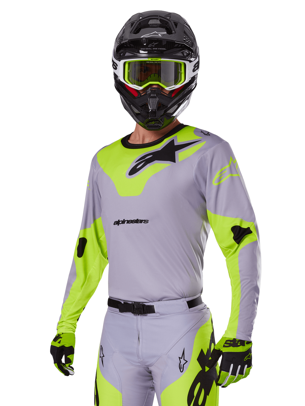Piloto de motocross con el conjunto Alpinestars 2025 Racer Veil en gris y verde flúor, jersey y pantalones gris claro con paneles llamativos en verde neón y logotipos de Alpinestars en negro, coordinado con guantes a juego y un casco negro con gafas verde neón, equipamiento profesional para carreras todoterreno.
