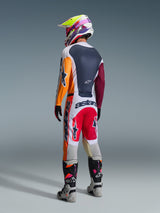 Motocross rider wearing complete racing gear from behind, Alpinestars 2026 Racer Portl Jersey in Red Light Gray and Dark Green with orange and maroon panels, matching white and red pants, gray and black boots with pink details, multicolored helmet, coordinated off-road racing outfit.
