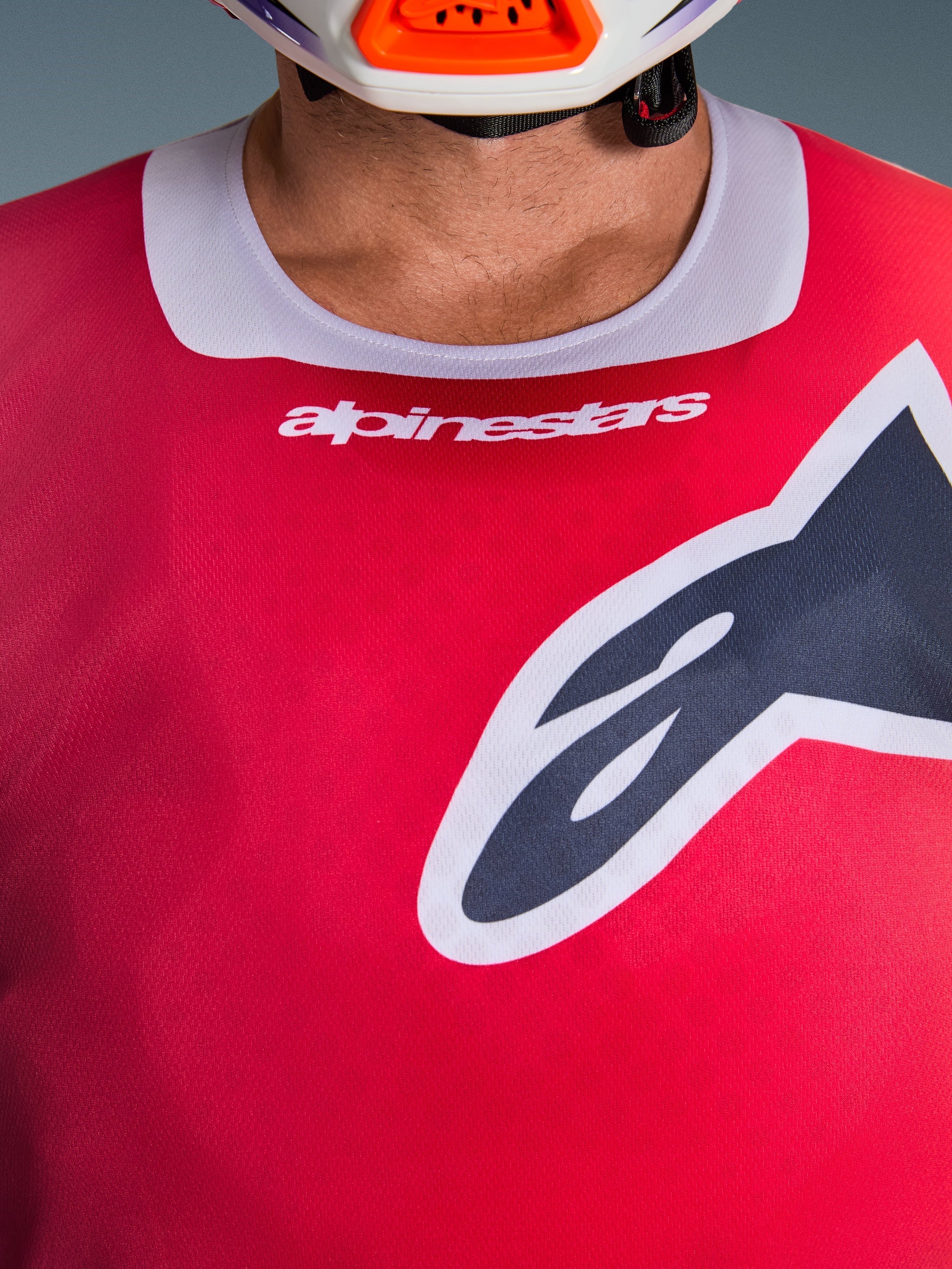 Close-up of the Alpinestars 2026 Racer Portl Jersey in Red, featuring a light gray stretch collar with white branding and a large black Astars logo on the chest, performance motocross racing gear
