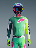 Alpinestars 2026 Racer Portl Jersey, jersey de motocross, verde, blanco y negro con un gran logotipo rosa de Alpinestars en el pecho, usado por un piloto con un casco multicolor vibrante y gafas a juego, equipamiento profesional para carreras todoterreno.
