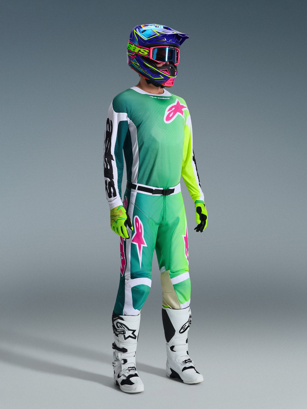 Piloto de motocross con equipamiento de carreras completo, Jersey Racer Portl 2026 en verde con mangas blancas y negras y logotipo rosa, pantalones verdes a juego con detalles en rosa, casco multicolor con gafas, botas blancas y negras y guantes verdes, conjunto coordinado para carreras todoterreno