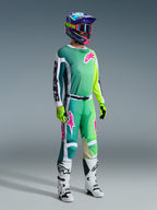 Alpinestars 2026 Racer Portl Gear Set, Motocross rider in teal to lime green gradient jersey with pink logos and white sleeves, matching green and white pants, colorful graphic helmet with pink goggles, white boots, and fluorescent yellow gloves, professional off-road racing kit.