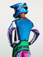 Jersey Alpinestars Techstar Maven, jersey de motocross para hombre, azul y verde con detalles rosa, vista trasera de modelo con chasis elástico y ventilación láser.