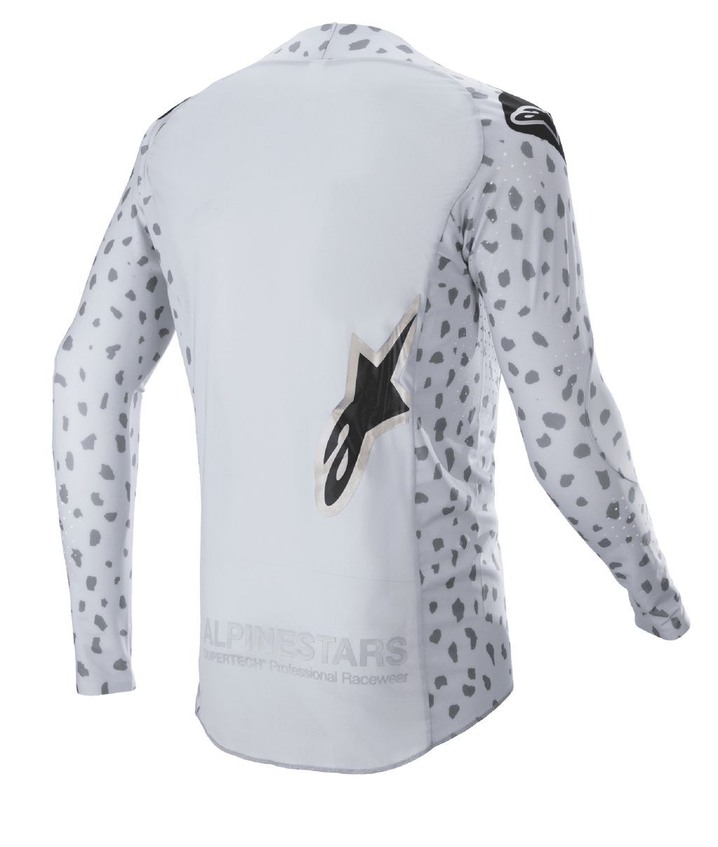 Alpinestars 2023 Supertech North Jersey, jersey de motocross, gris Haze y negro, vista trasera con un patrón de manchas abstractas en las mangas y los laterales, logotipo de estrella grande, panel trasero extendido y construcción de rendimiento transpirable
