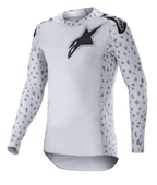 Alpinestars 2023 Supertech North Jersey, camiseta de motocross, gris Haze y negro, camiseta de manga larga blanca con patrón de manchas grises en las mangas y los laterales, logotipo de estrella negro en el pecho y los hombros, malla elástica de alto rendimiento con dobladillo curvo