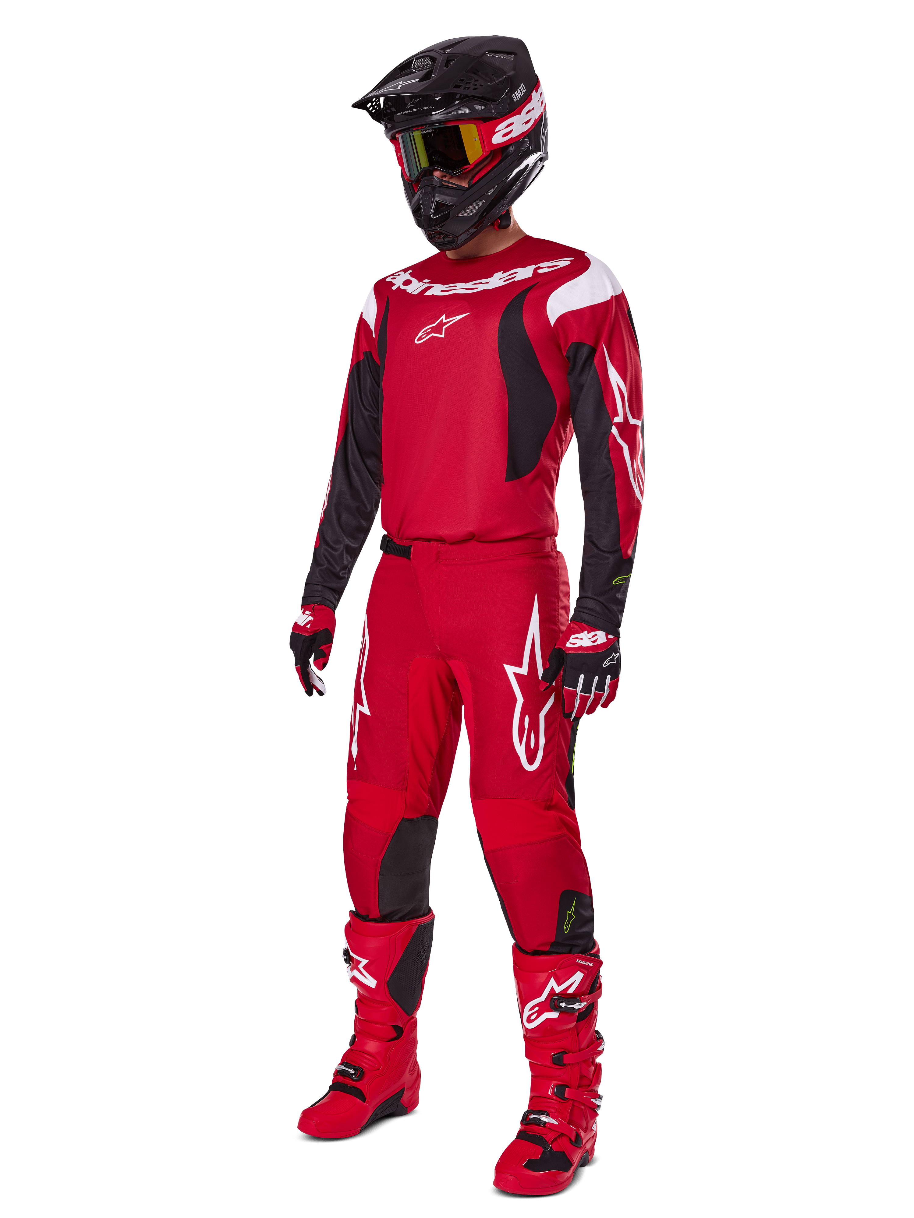 Piloto de motocross con el conjunto de equipamiento Alpinestars Fluid Haul 2025, rojo brillante con detalles en negro y blanco, equipo completo que incluye jersey, pantalones, casco, botas y guantes, diseñado para el rendimiento y la protección todoterreno