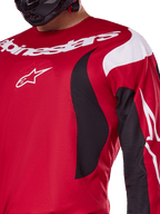 Alpinestars 2025 Fluid Haul Jersey, rojo brillante y negro, vista de cerca del pecho y el brazo con marca y logotipo de Alpinestars en blanco, diseño ergonómico atlético con detalles dinámicos en blanco y negro para rendimiento en motocross.