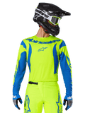 Alpinestars 2025 Fluid Haul Jersey, jersey de motocross, amarillo neón y azul, con logotipo de Alpinestars azul en el pecho, usado con equipo a juego que incluye casco negro y guantes azules, ajuste atlético para conducción off-road
