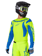 Alpinestars 2025 Fluid Haul Gear Set, Motocross Jersey and Pants, Bright Yellow and Blue, worn with a black helmet and yellow-framed goggles, features wave-like blue patterns on the sleeves and blue star logos on the pants, coordinated off-road racing outfit