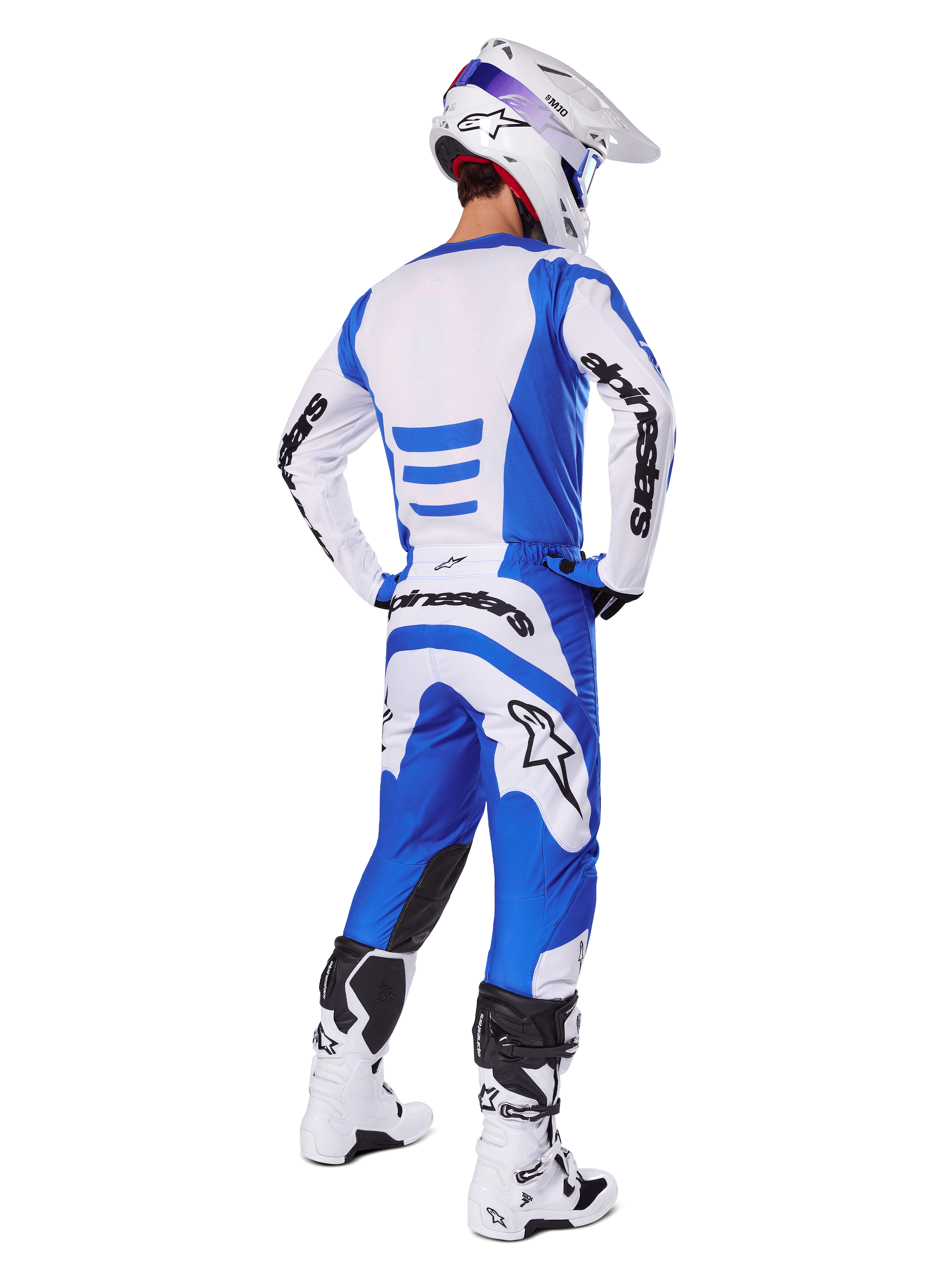 Motocross rider from the back wearing the Alpinestars 2025 Fluid Haul Gear Set, Blue and White jersey with matching pants, white helmet with blue accents, and white and black racing boots, coordinated off-road racing outfit