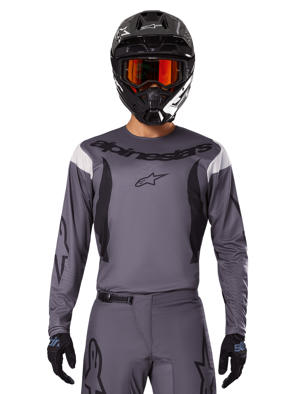 Piloto de motocross con el Jersey Fluid Haul 2025 y conjunto de equipo, gris con detalles en negro y blanco, con mangas largas y logotipos llamativos, casco negro con gafas naranjas y guantes negros, atuendo coordinado para carreras todoterreno