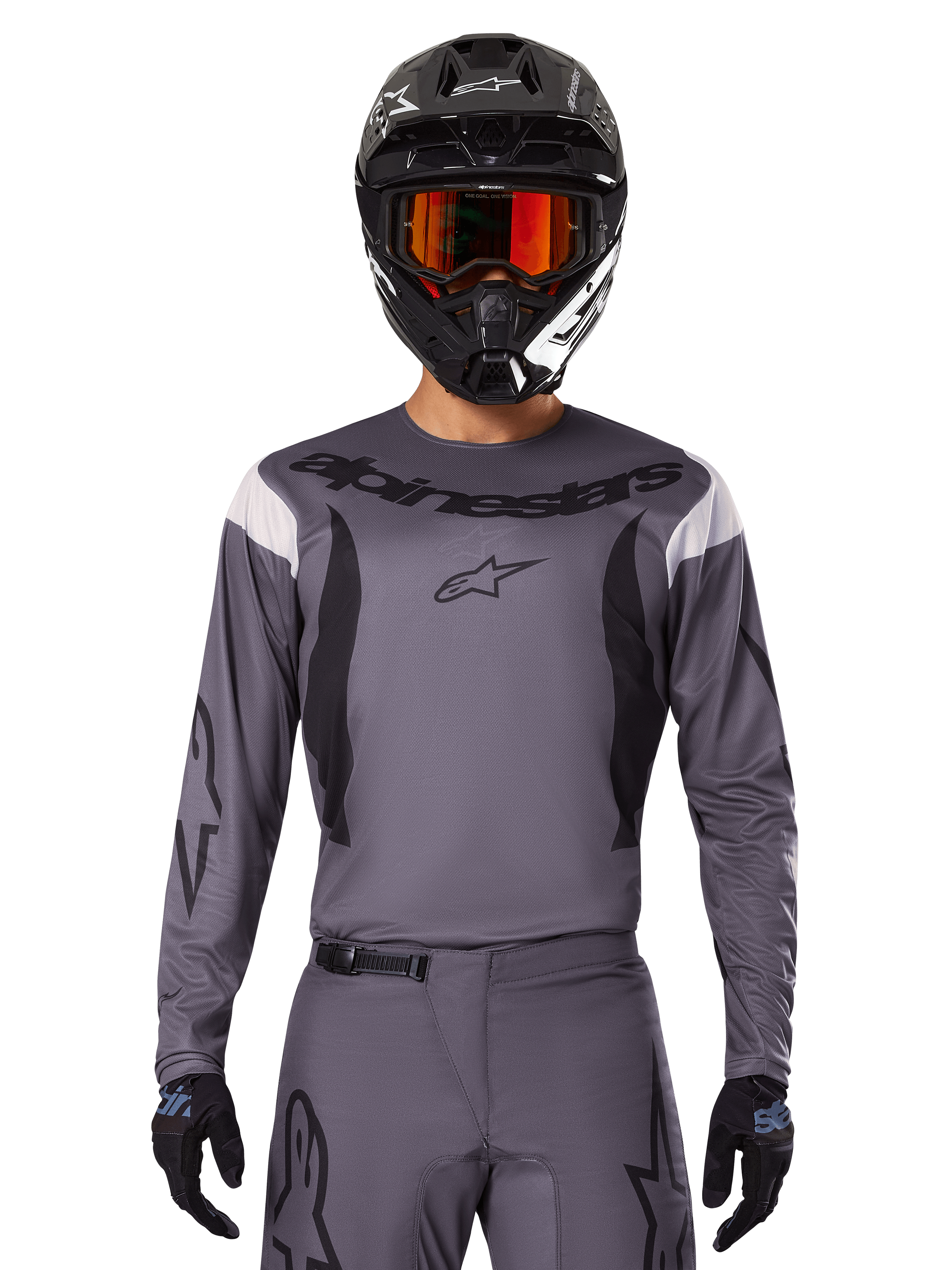 Piloto de motocross con el Jersey Fluid Haul 2025 y conjunto de equipo, gris con detalles en negro y blanco, con mangas largas y logotipos llamativos, casco negro con gafas naranjas y guantes negros, atuendo coordinado para carreras todoterreno