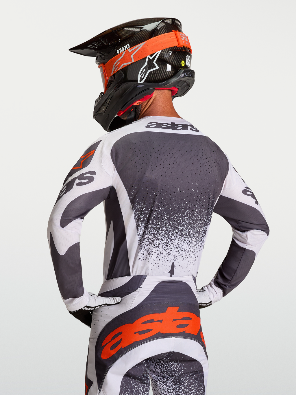 Jersey Techstar Swan, jersey de motocross para hombre, gris oscuro y blanco, con detalles rojos y logotipo Astars, ajuste de carrera atlético, visto desde atrás en piloto.