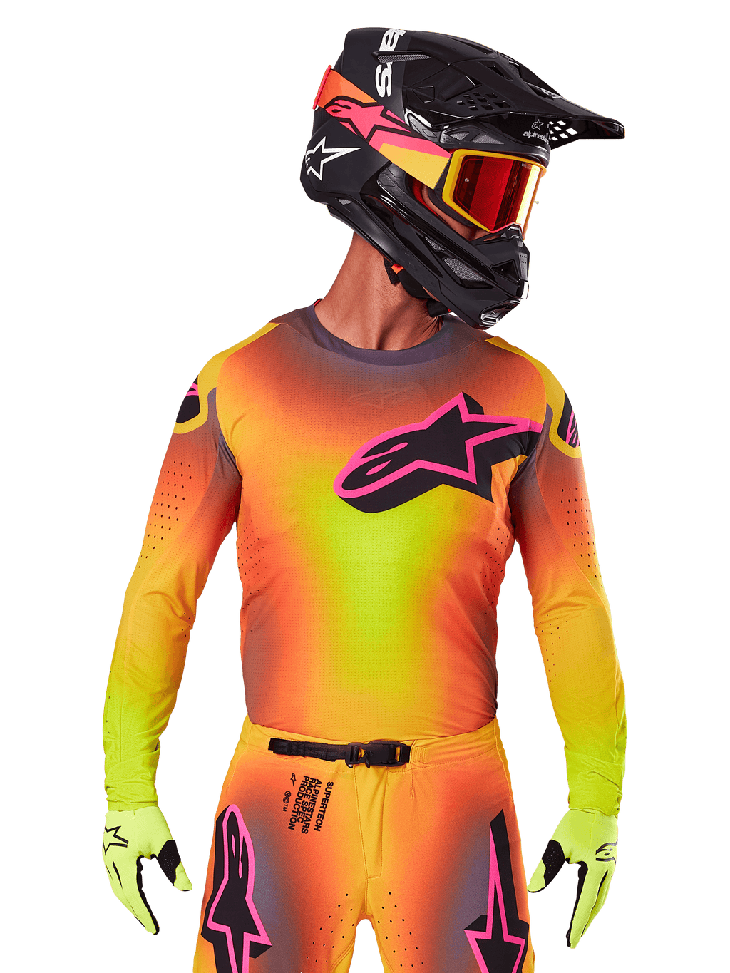 Piloto de motocross con el Jersey Supertech Lipan 2025, degradado vibrante en amarillo, naranja y rosa, gran logotipo de estrella de Alpinestars negro con contorno rosa en el pecho, perforaciones cortadas con láser para ventilación, ajuste atlético de competición, combinado con pantalones a juego, guantes amarillos y casco negro con gafas.