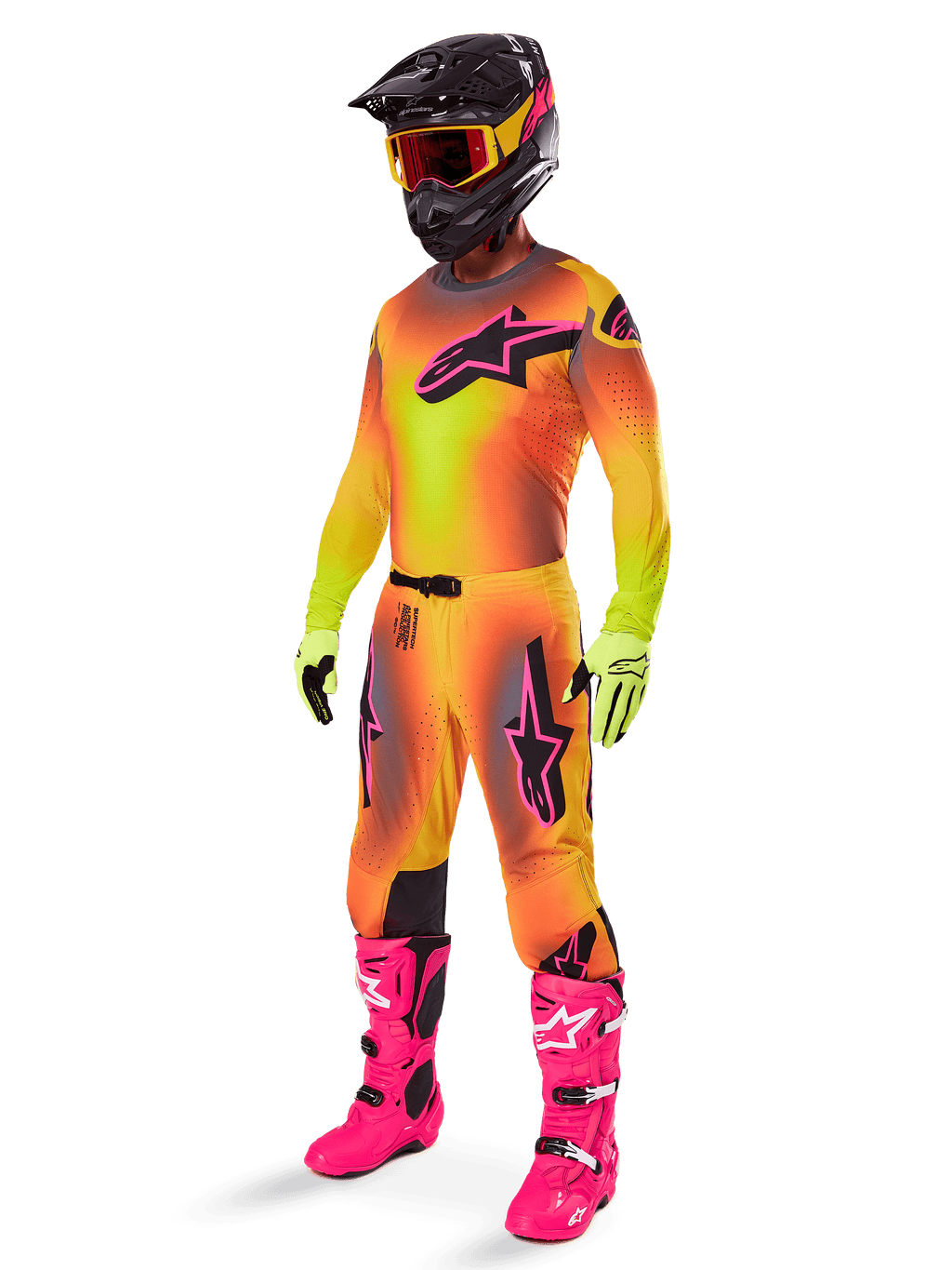 Piloto de motocross con el conjunto de equipamiento Alpinestars Supertech Lipan 2025, jersey y pantalones con degradado amarillo y naranja y detalles en rosa, casco negro con gafas amarillas y rojas, guantes amarillo brillante y botas rosa vibrante, traje de carreras todoterreno coordinado