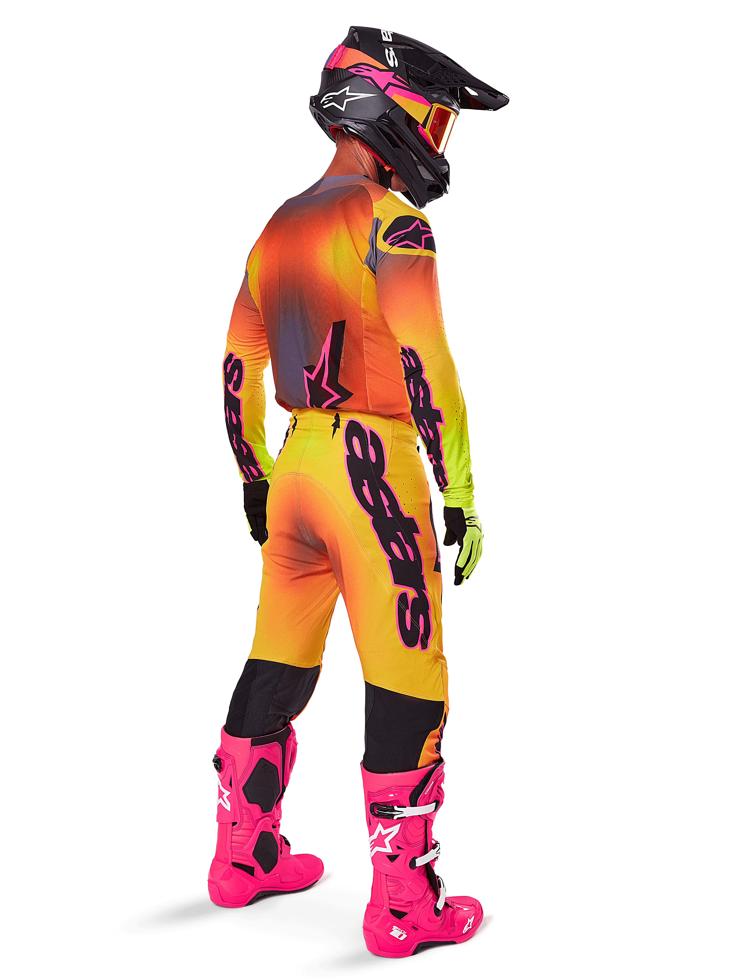 Motocross rider from behind wearing the Alpinestars 2025 Supertech Lipan Gear Set, yellow and orange gradient jersey with pink accents, matching pants, bright pink boots, and a black helmet with pink and yellow graphics, coordinated outfit for professional racing