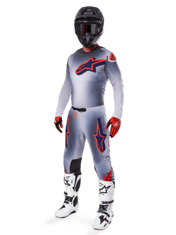 Alpinestars 2025 Supertech Lipan Gear Set, conjunto de equipo para motocross, gris con gráficos de estrellas en naranja flúor y azul marino, usado con casco negro, guantes rojos y negros, y botas blancas y negras, equipamiento profesional completo para off-road con diseño ventilado