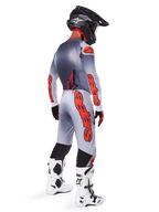 Motocross rider from behind wearing the 2025 Supertech Lipan Gear Set, Gray and Orange Fluo jersey with matching pants, bold orange Alpinestars branding on sleeves and legs, black helmet, white and black motocross boots, coordinated professional off-road racing outfit.