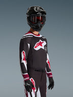 Piloto de motocross con el jersey Alpinestars Supertech AFD Vista 2026 en negro, rojo y blanco, con un gran logotipo de estrella roja en el pecho y perforaciones cortadas con láser, combinado con un casco negro y pantalones de carreras a juego para un rendimiento todoterreno