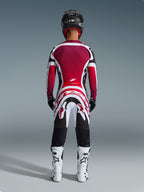 Piloto de motocross visto desde atrás con el Jersey Supertech AFD Vista 2026 en negro, rojo y blanco, combinado con pantalones de motocross a juego, casco negro y botas blancas, conjunto completo de equipamiento profesional para competición off-road