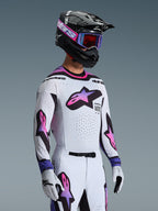 Piloto de motocross con el Jersey Supertech AFD Vista 2026 en blanco, púrpura y negro, pantalones a juego en blanco y púrpura, casco negro con gafas púrpuras y guantes blancos, equipamiento completo profesional para carreras off-road.
