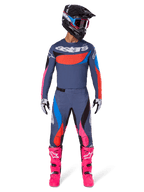 Alpinestars 2025 Techstar Dreem Gear Set, piloto de motocross con equipamiento completo de competición, jersey y pantalones azul grisáceo con detalles vibrantes en rosa, naranja y azul cian, logotipo 'astars' grande en el pecho, botas rosa brillante, casco negro con gafas, conjunto coordinado para motocross profesional