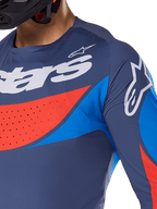 Primer plano del Jersey Alpinestars Techstar Dreem 2025, azul marino con detalles en azul vibrante y naranja, logotipos de Alpinestars en blanco en el pecho y el hombro, con perforaciones cortadas a láser para ventilación