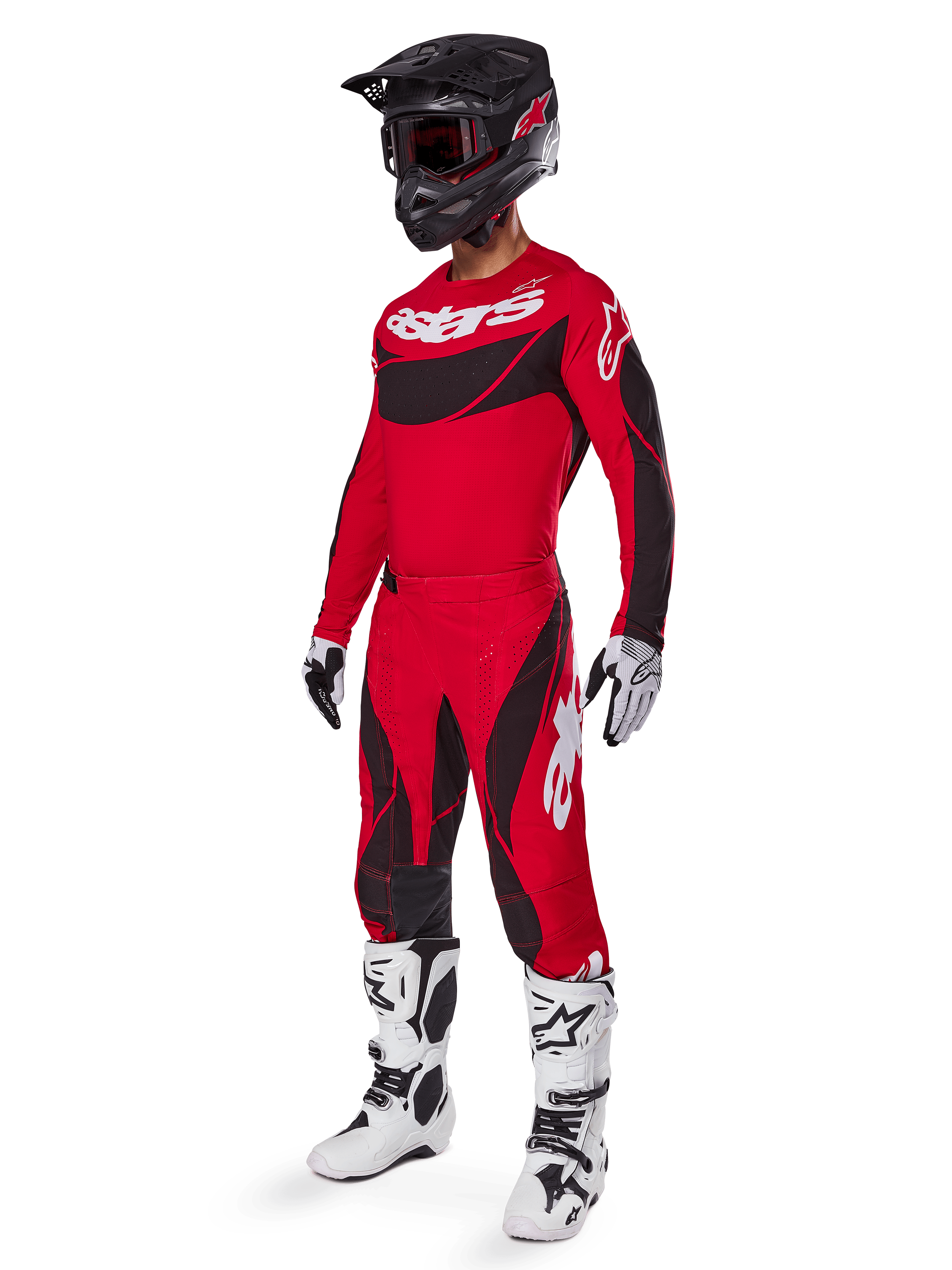Vista de cuerpo completo de un piloto de motocross con el conjunto de equipo Techstar Dreem 2025 en rojo brillante y negro, que incluye un jersey de alto rendimiento con logotipos blancos, pantalones de tejido ripstop elástico a juego, casco negro con visera roja, guantes blancos y negros y botas Tech blancas, traje de carreras especializado para competición todoterreno.