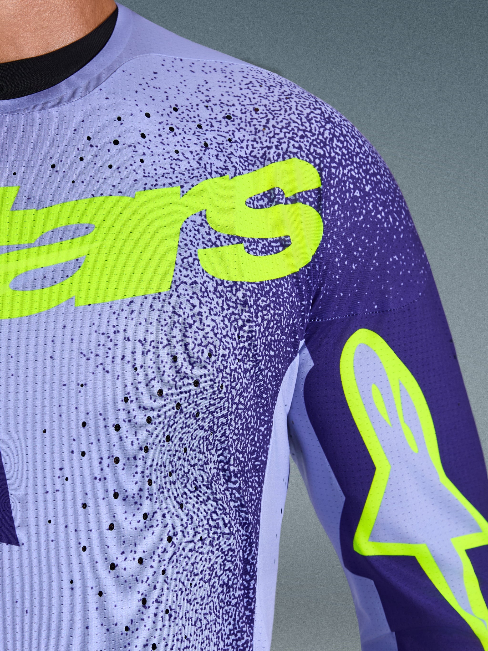 Jersey Alpinestars Supertech Scenz 2026, jersey de motocross, morado y amarillo flúor, vista en primer plano que muestra el material de malla elástica perforada y el logotipo de Alpinestars en amarillo brillante en el pecho y la manga